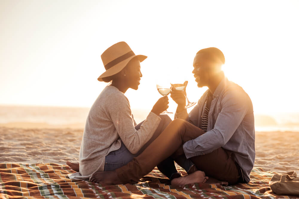 A photo of a couple sipping wine on the beach on their Cape Cod honeymoon