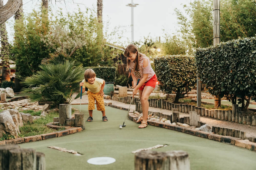 Two kids playing mini golf at a Cape Cod course.