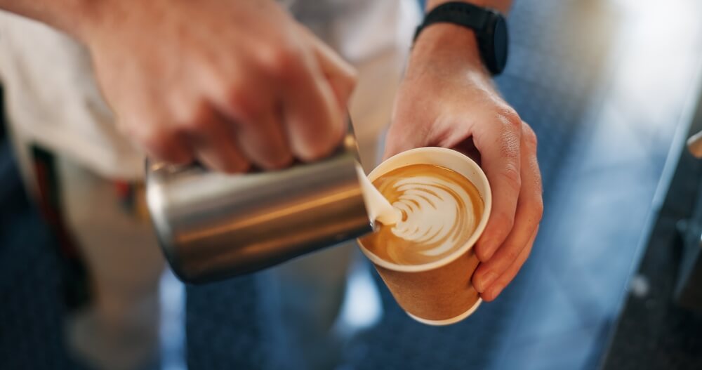 A person pouring a cup of coffee at Cape Cod coffee shop.